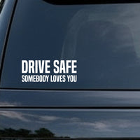 White vinyl decal with bold uppercase letters reading Drive Safe Somebody Loves You on a black background in a simple block style.