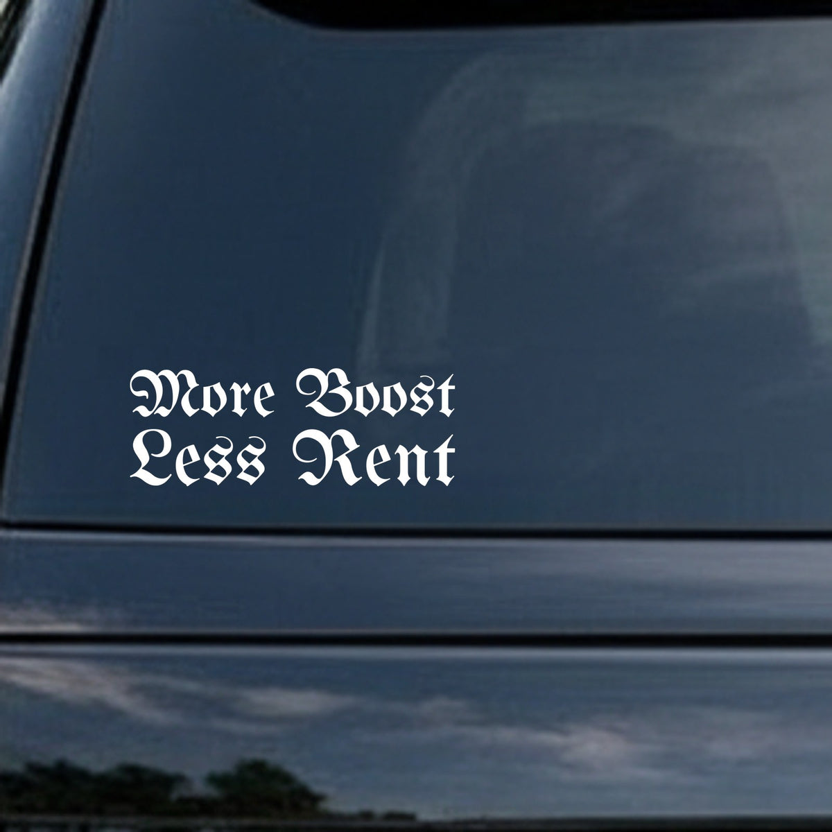 White vinyl decal with the phrase More Boost Less Rent in gothic blackletter Old English style font on black background.