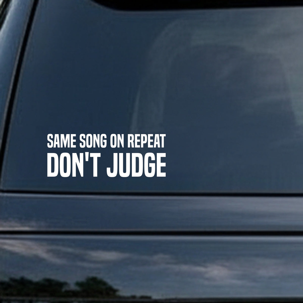 Bold white text on black background saying Same Song On Repeat Don't Judge in all capital letters for a vinyl decal