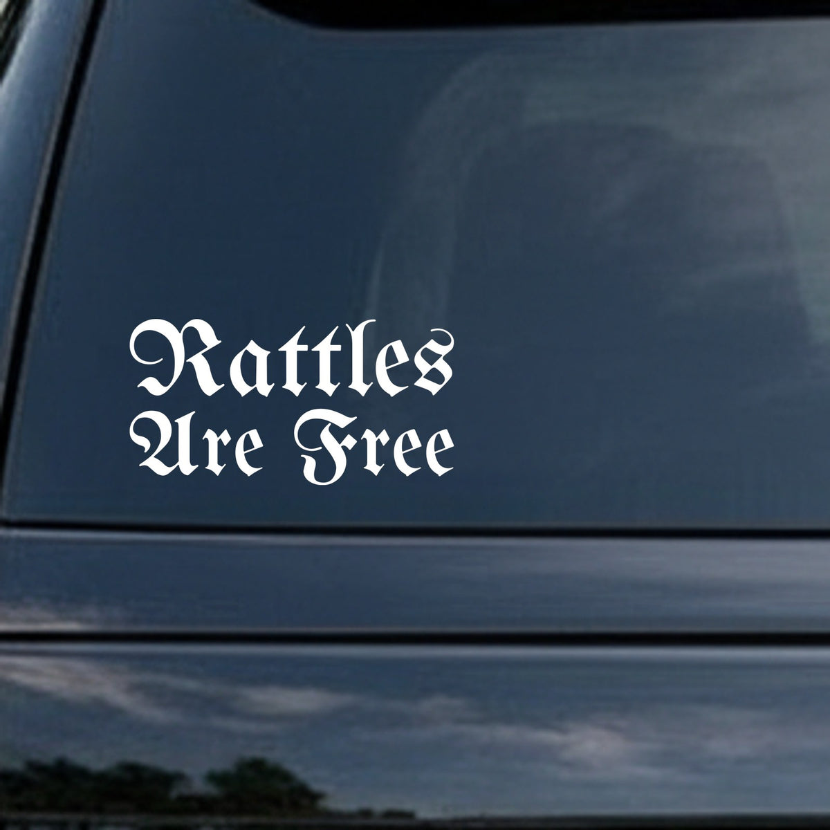 White gothic Old English lettering spelling out 'Rattles Are Free' on a black background in a vinyl decal style.