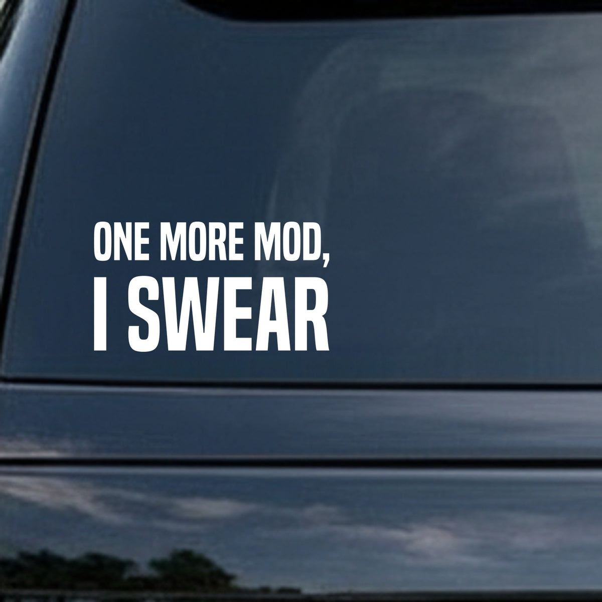 White vinyl decal with bold uppercase text saying 'ONE MORE MOD, I SWEAR' on a black background in a simple block font.