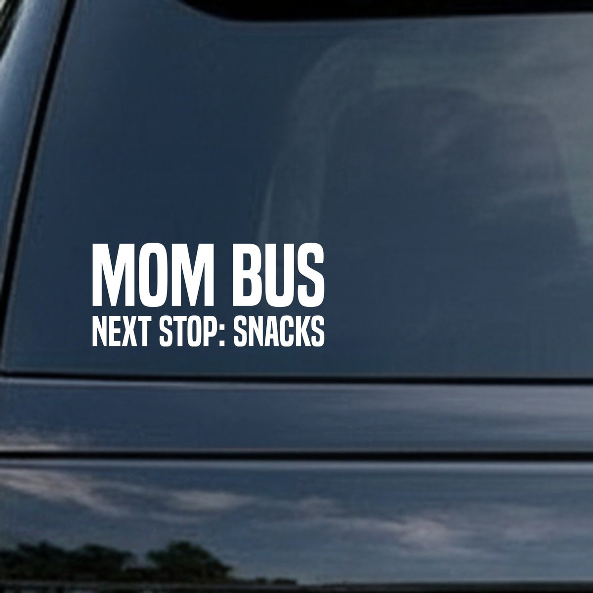 White vinyl decal with bold text reading 'Mom Bus Next Stop: Snacks' on black background in two stacked lines