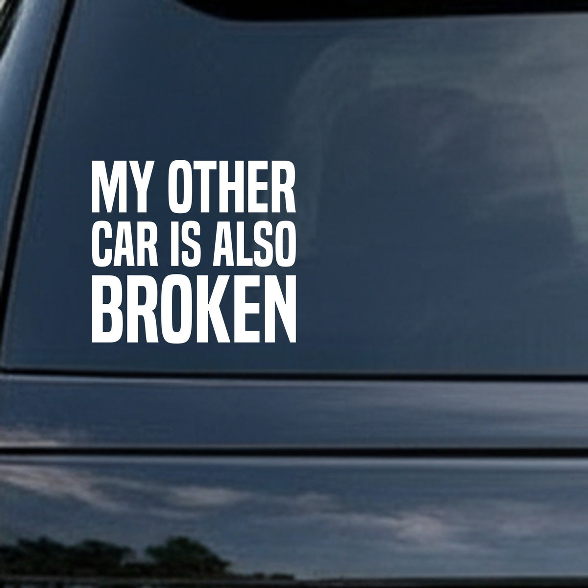 White bold text saying My Other Car Is Also Broken on a black background in a simple block style