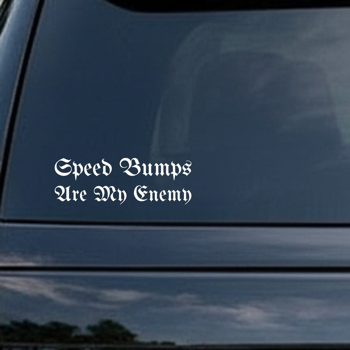 White vinyl decal with the phrase Speed Bumps Are My Enemy in gothic Old English font on a black background