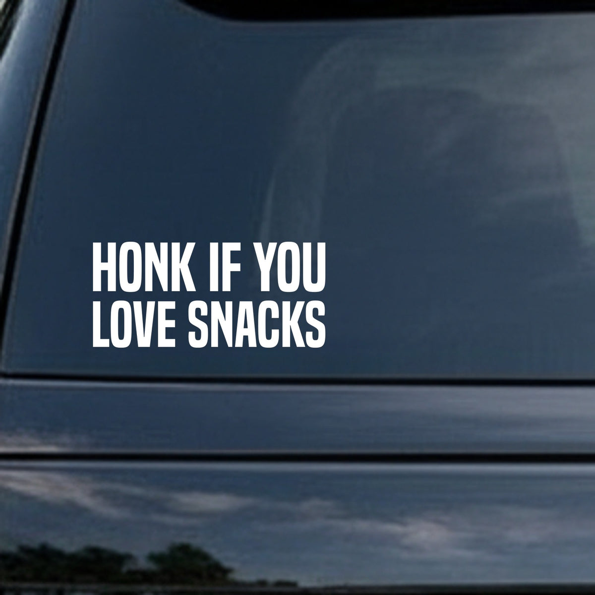 White bold text decal on black background reading Honk If You Love Snacks in all capital letters.