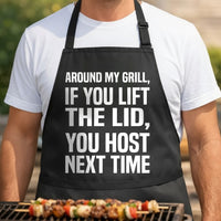 Black apron with large bold white text saying if you lift the lid you host next time in a simple block font