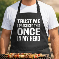 Black apron with large bold white text reading Trust Me I Practiced This Once In My Head in block letters