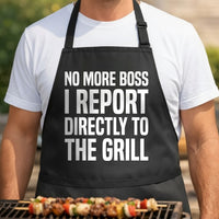 Black apron with large white block text saying No More Boss I Report Directly To The Grill in bold font