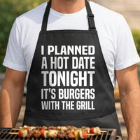Black apron with bold white text saying Planned A Hot Date Tonight It's Burgers With The Grill in large block letters