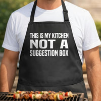 Black apron with bold white text saying This Is My Kitchen Not A Suggestion Box in block letters