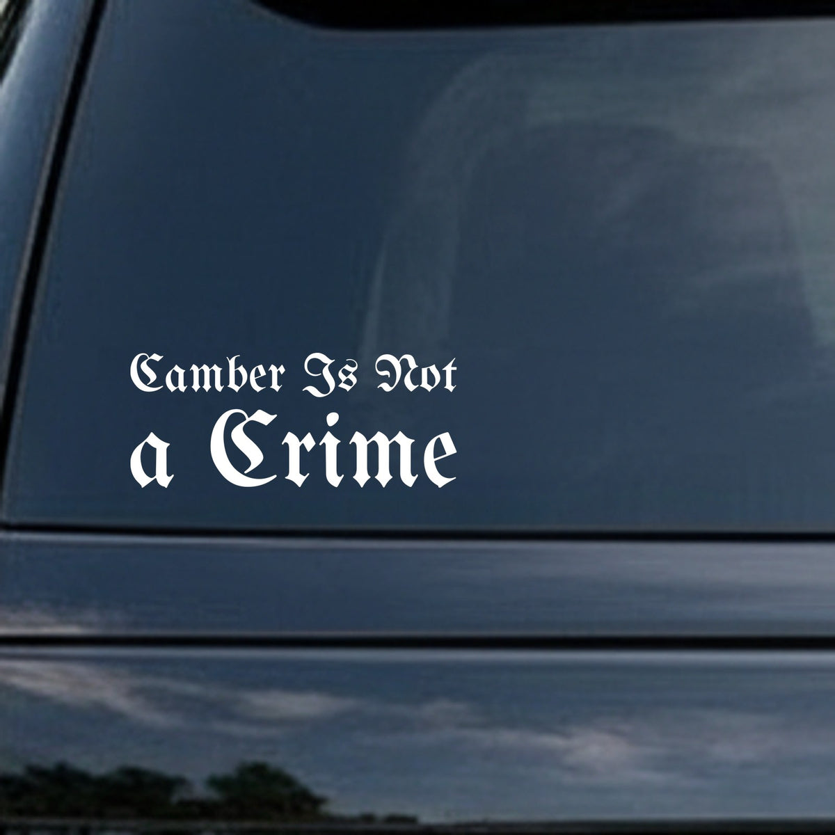White gothic blackletter lettering saying 'Camber Is Not A Crime' on a black background in bold Old English style font.