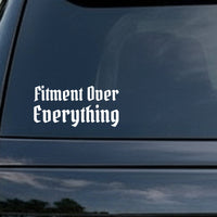 White vinyl decal with the phrase Fitment Over Everything in gothic blackletter Old English font on a black background.