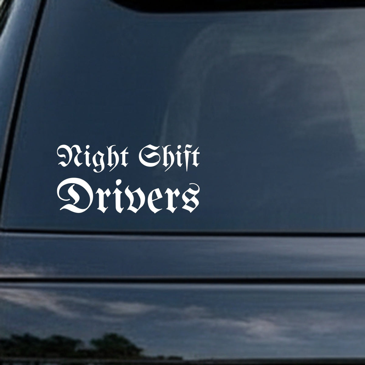 White gothic blackletter Old English font saying Night Shift Drivers on a black background in two lines.