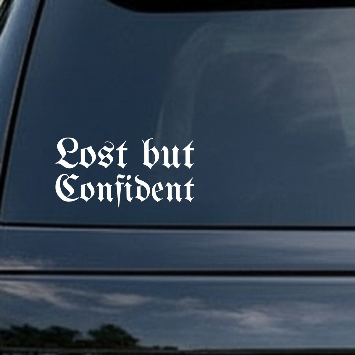 White gothic blackletter lettering spelling Lost but Confident on a black background in Old English style font