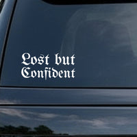 White gothic blackletter lettering spelling Lost but Confident on a black background in Old English style font