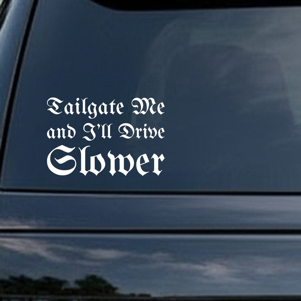 White gothic blackletter lettering saying Tailgate Me and I'll Drive Slower on black background in Old English style font