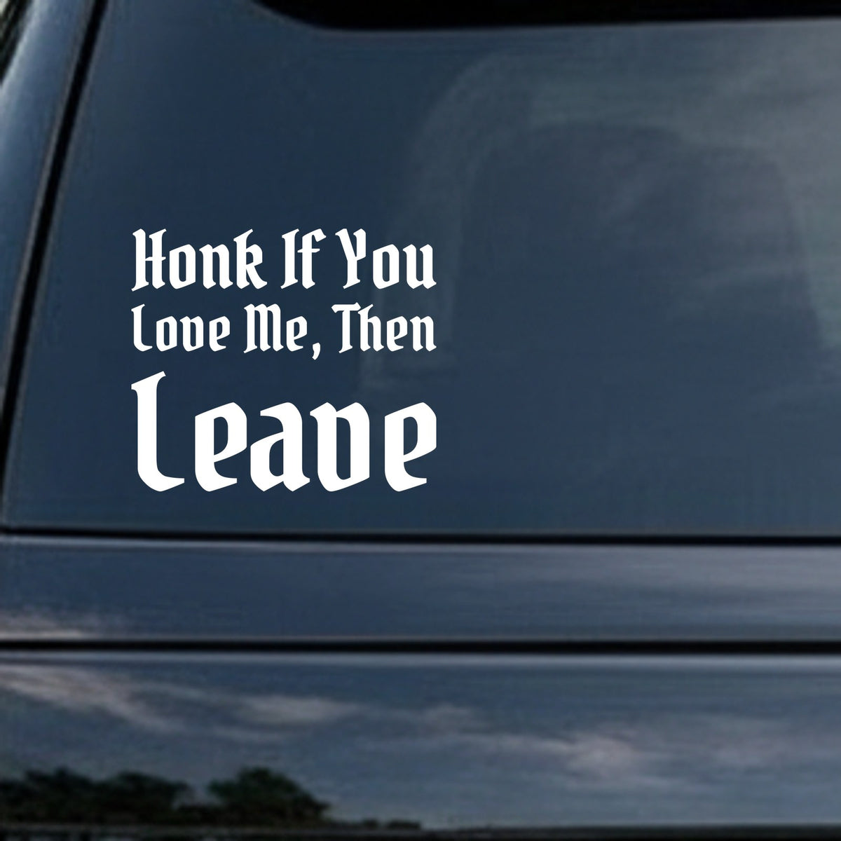 White gothic blackletter text saying Honk If You Love Me Then Leave on a black background in bold Old English style font