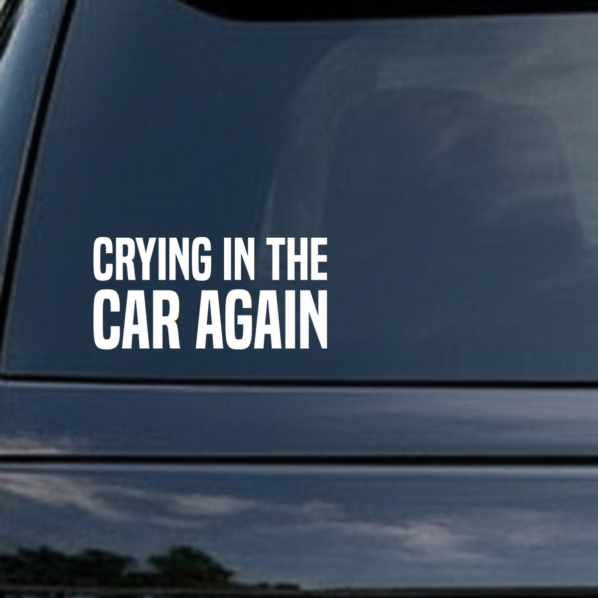 White block letters saying Crying In The Car Again on a black background in a bold sans serif font