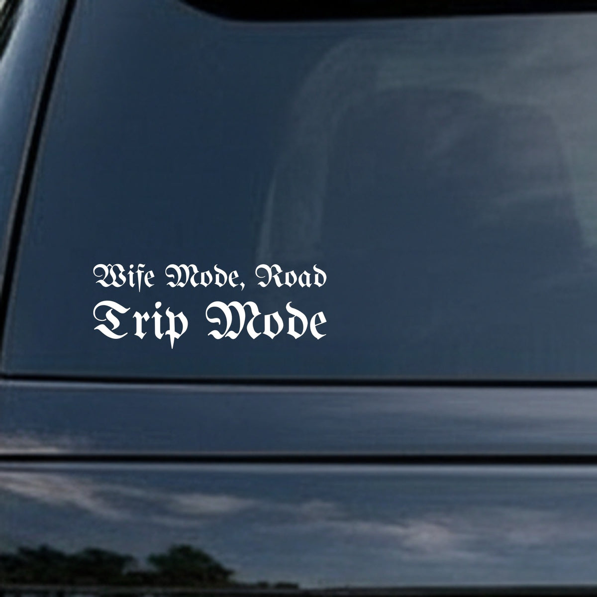 White gothic blackletter lettering spelling out 'Wife Mode, Road Trip Mode' on a black background in Old English style