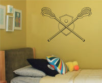 Black and white line art of two crossed lacrosse sticks with shield and ball in center in simple sports illustration style