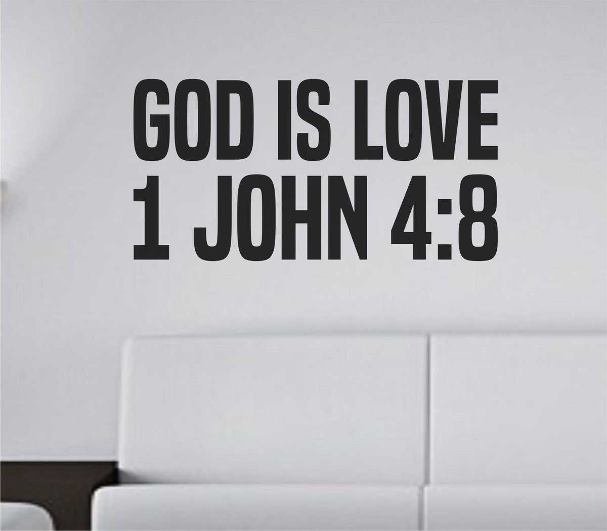 Bold black vinyl wall decal with tall block letters spelling God Is Love from 1 John 4:8 in a simple home setting.