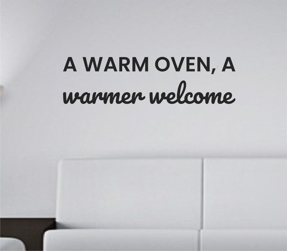 Black vinyl wall decal with the quote 'A warm oven, a warmer welcome' in a simple, modern font on a white background.