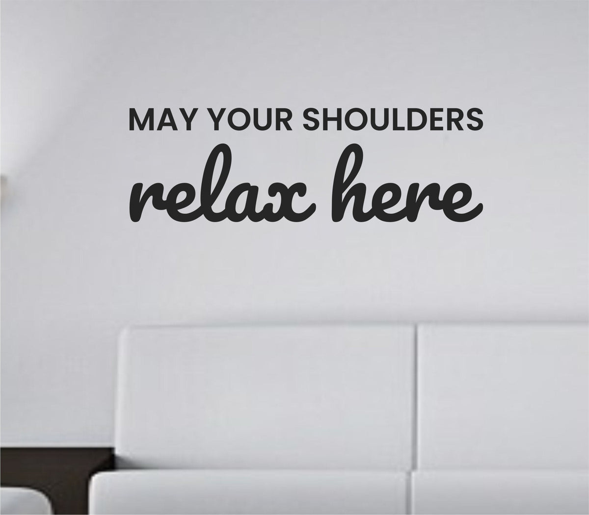 Black vinyl wall decal with the quote 'May your shoulders relax here.' on a white background in simple modern lettering.