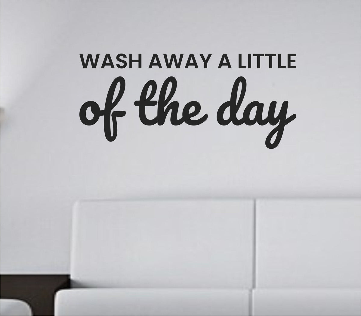 Black vinyl wall decal with the phrase 'Wash away a little of the day.' in a clean, modern font on a white background.