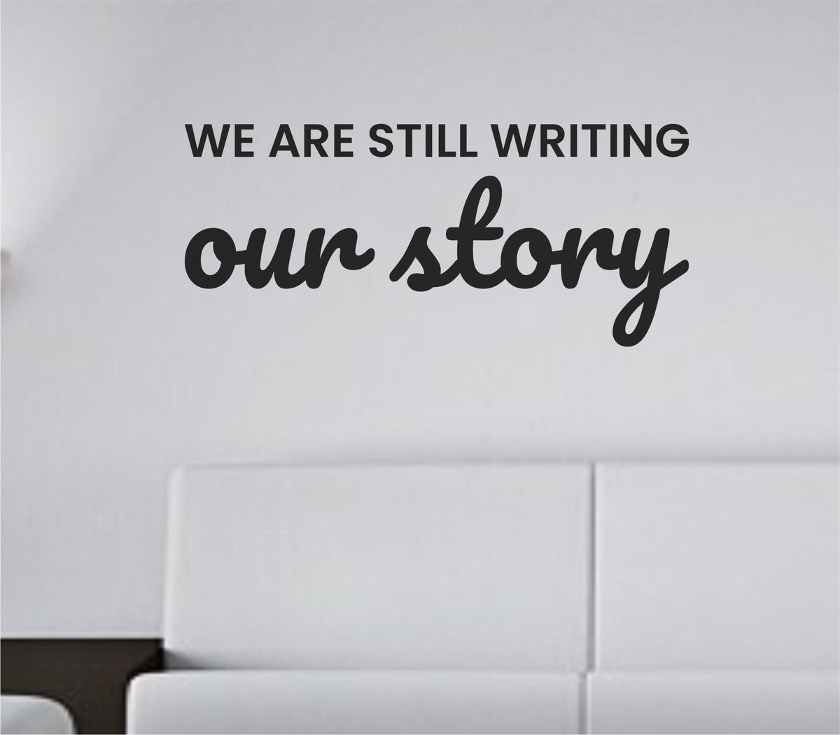 Black vinyl wall decal displaying the phrase 'We are still writing our story' in a simple modern font on a white background.