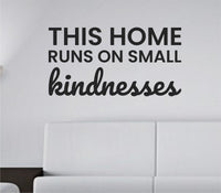 Black vinyl wall decal quote reading "This home runs on small kindnesses" on white background in simple elegant font
