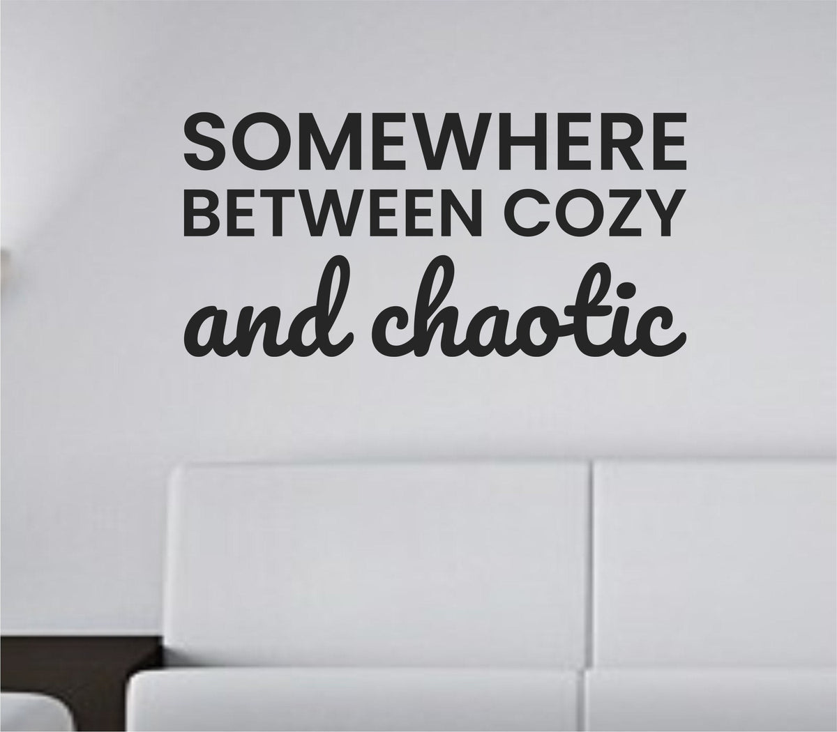 Black vinyl wall decal with the quote 'Somewhere between cozy and chaotic' in a casual script style on a white background.