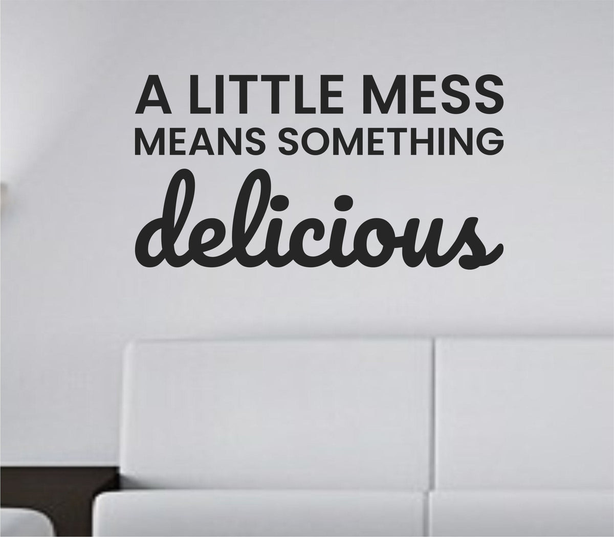 Black vinyl wall decal with the quote 'A Little Mess Means Something Delicious' in simple, modern script on a white background.