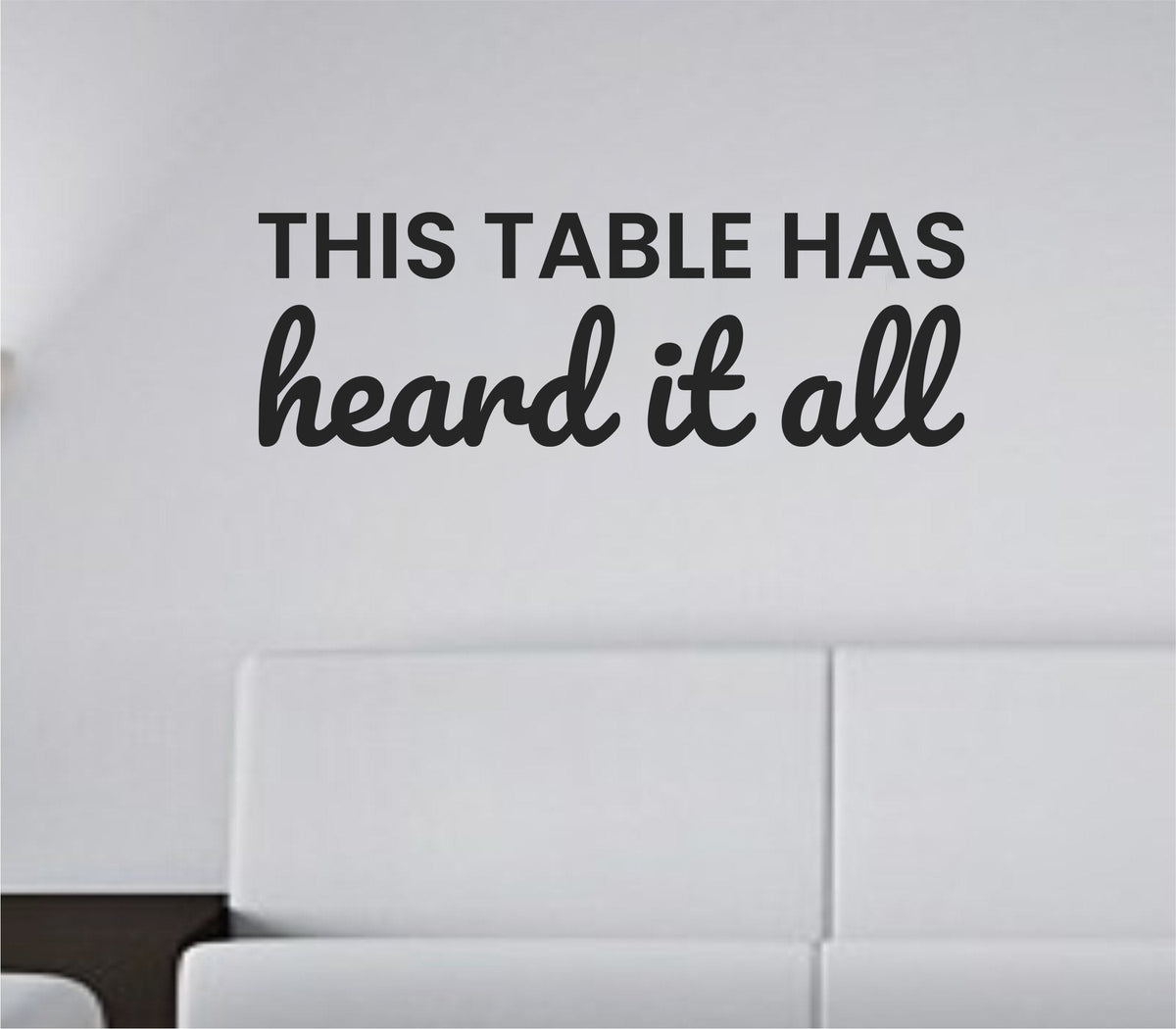 One-color vinyl wall decal with the quote 'This table has heard it all.' in simple black text on a white background.