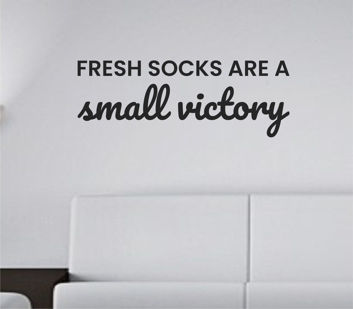 Black vinyl wall decal with the phrase 'Fresh socks are a small victory' in simple modern font on a white background.