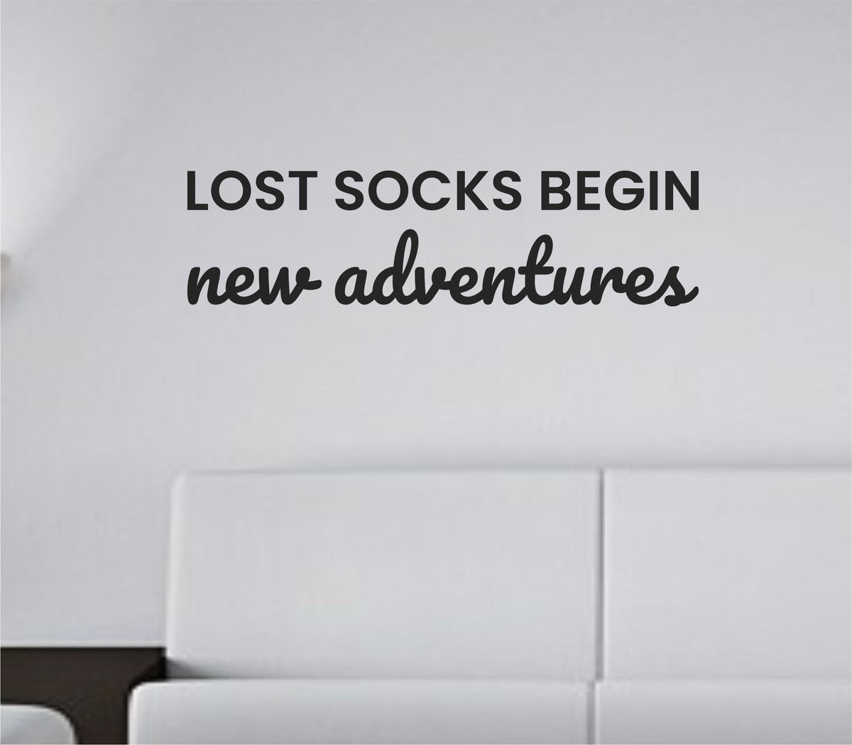 Black vinyl wall decal with the quote "Lost socks begin new adventures." displayed on a white background in a clean, modern font