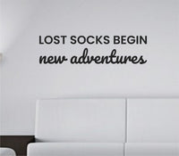 Black vinyl wall decal with the quote "Lost socks begin new adventures." displayed on a white background in a clean, modern font