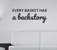 Black vinyl wall decal with the quote 'Every basket has a backstory.' in clean modern lettering on white background