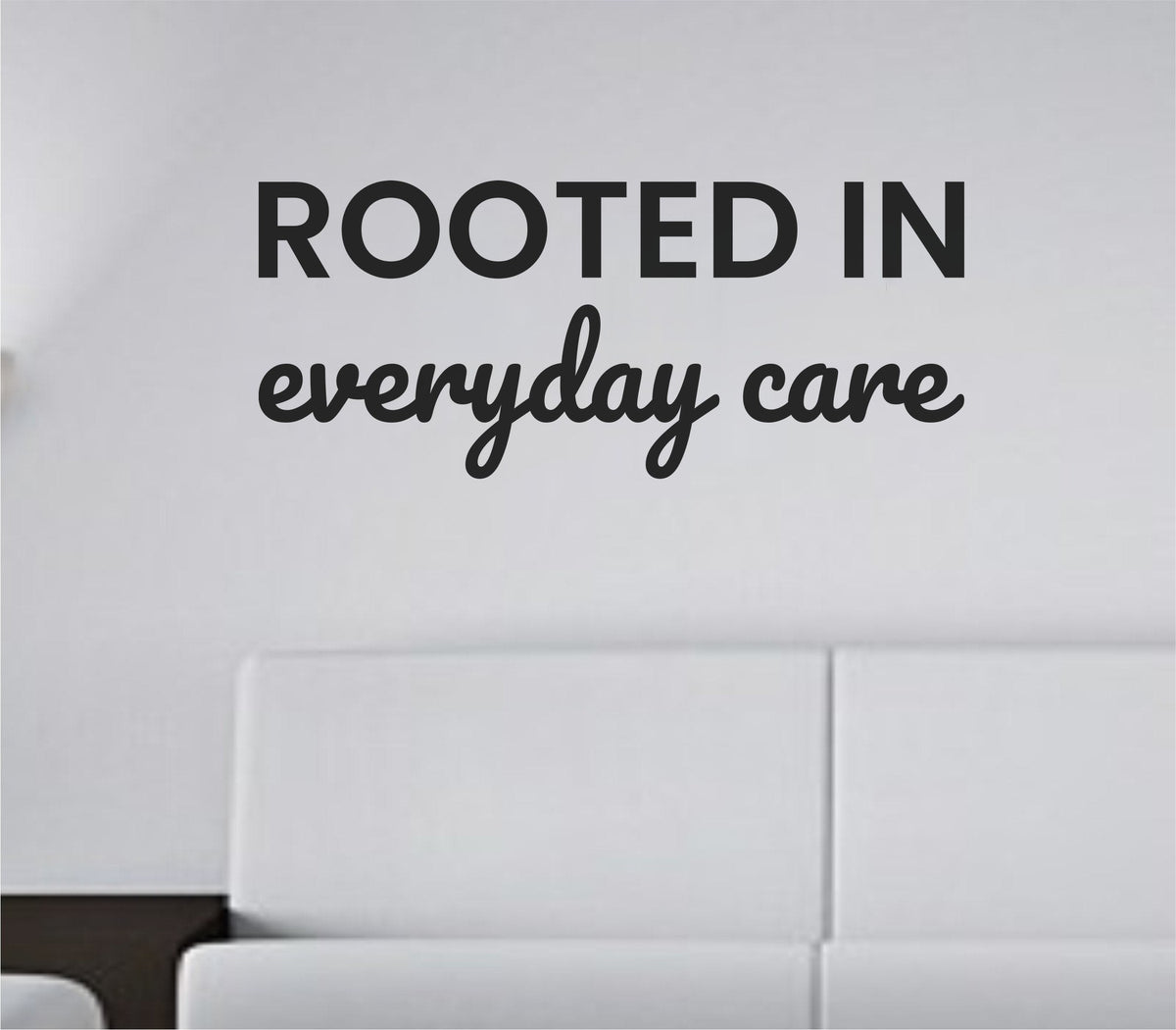 Black one-color vinyl wall decal with the quote 'Rooted in everyday care.' in simple, modern typography on white background.