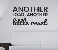 Black vinyl wall decal with the phrase 'Another load, another little reset.' in simple modern font on a white background.
