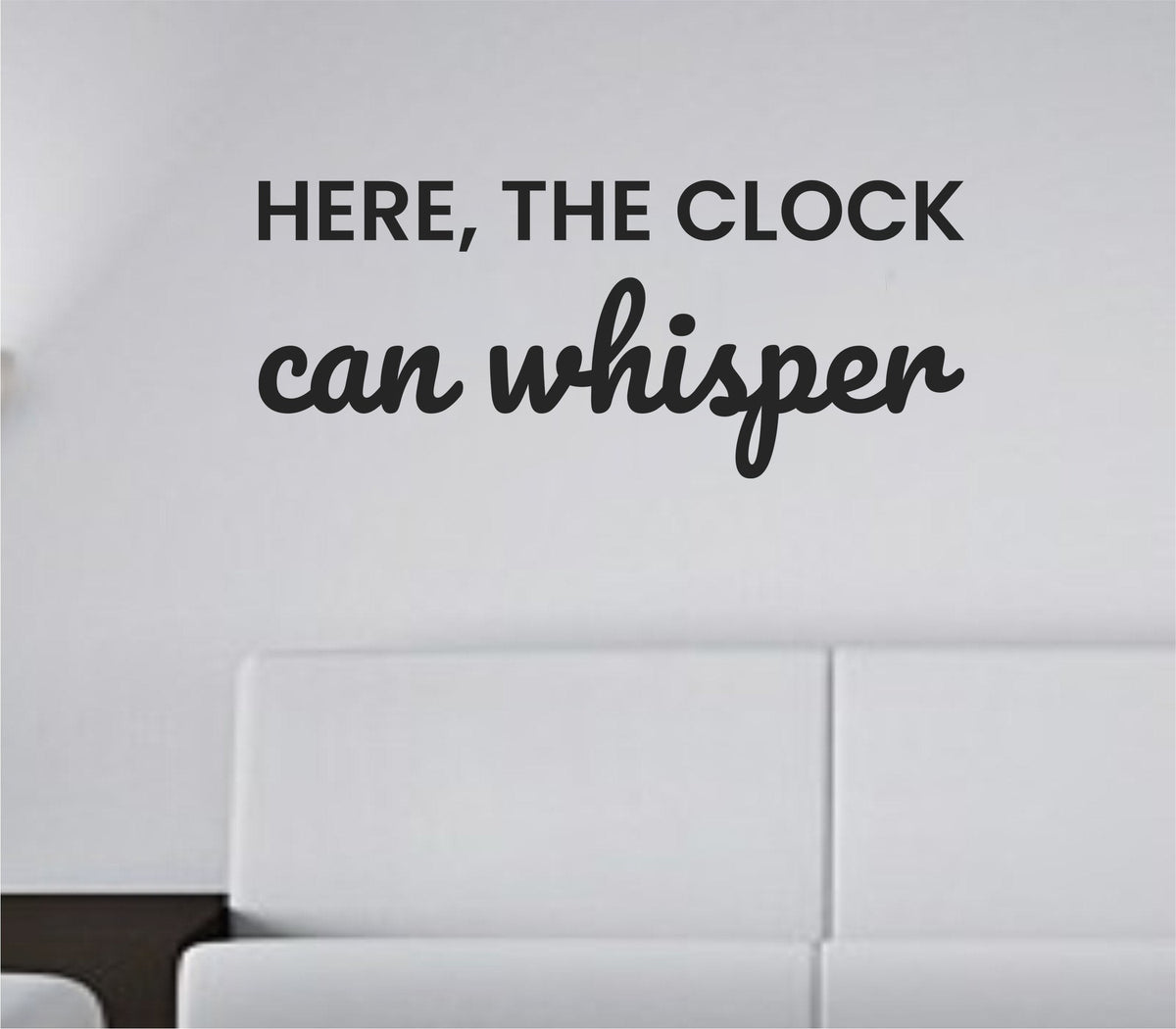 Black vinyl wall decal with the phrase Here, the clock can whisper in simple, calm typography on a white background.