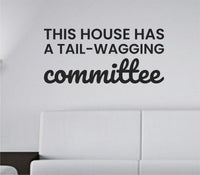 Black vinyl wall decal displaying the text 'This house has a tail-wagging committee' in playful, bold font on a white background.