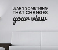 Black vinyl wall decal with the quote Learn something that changes your view in clean, bold lettering on a white background.