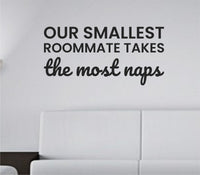 Black vinyl wall decal with the phrase Our smallest roommate takes the most naps in playful, bold lettering on a white background.