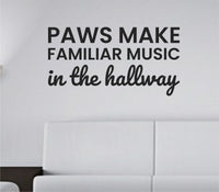 Black vinyl wall decal with the quote 'Paws Make Familiar Music In The Hallway' in a playful, clean font on a white background.