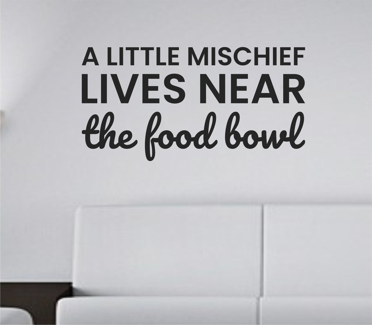 Black vinyl wall decal with the quote 'A little mischief lives near the food bowl' in playful script on a white background.