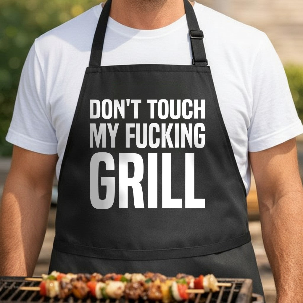 Black apron with bold white text reading Don't Touch My Fucking Grill in all caps, simple and direct design.