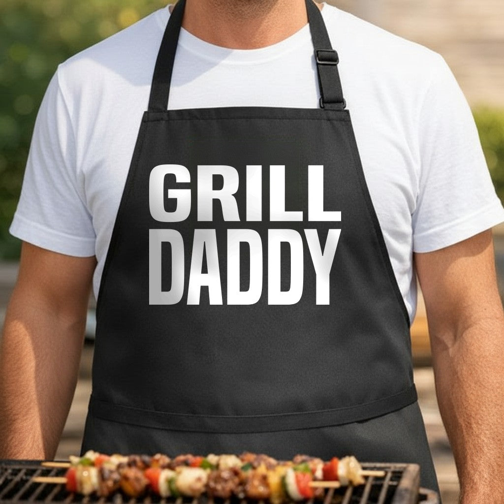 Black BBQ apron with large white block letters spelling Grill Daddy in a bold, simple font for grilling humor