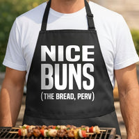 Black BBQ apron with large white text saying Nice Buns the Bread Perv in bold block letters, humorous kitchen apparel.