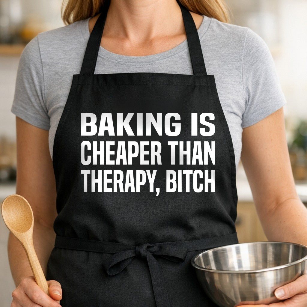 Black apron with large bold white text saying Baking Is Cheaper Than Therapy, Bitch in uppercase letters, simple typography style.