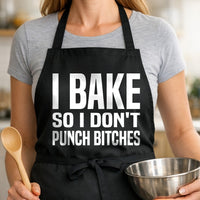 Black BBQ apron with large bold white text saying I Bake So I Don't Punch Bitches in a simple block font